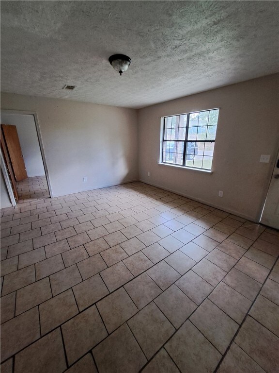 2106 Auburn St, Tuskegee, AL 36083 - tiled spare room featuring a textured ceiling and visible vents