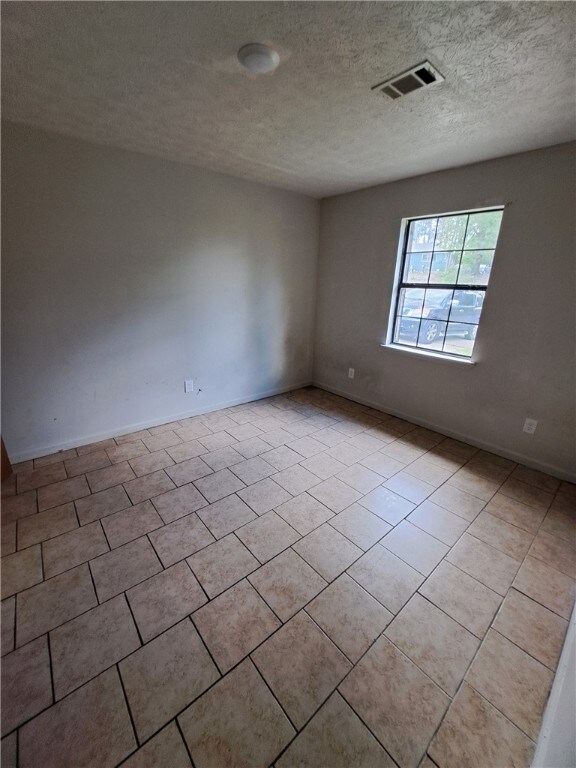 2106 Auburn St, Tuskegee, AL 36083 - spare room featuring tile patterned flooring, a textured ceiling, baseboards, and visible vents