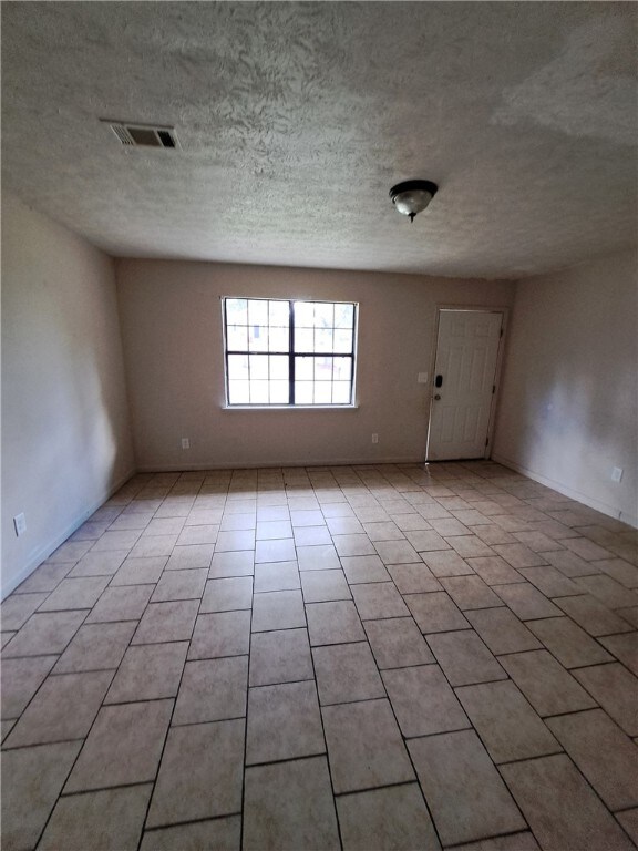 2106 Auburn St, Tuskegee, AL 36083 - empty room featuring a textured ceiling, visible vents, baseboards, and light tile patterned floors