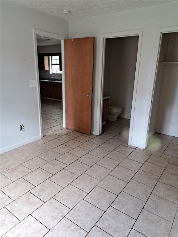 2106 Auburn St, Tuskegee, AL 36083 - unfurnished bedroom featuring a textured ceiling, a closet, and light tile patterned floors