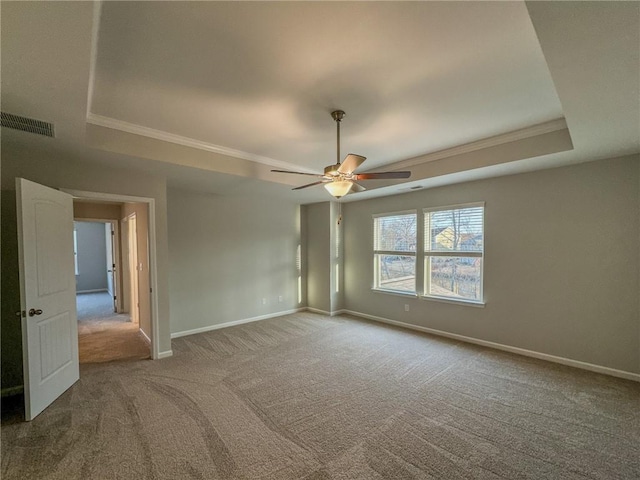 empty room featuring carpet flooring, a ceiling fan, visible vents, baseboards, and a tray ceiling