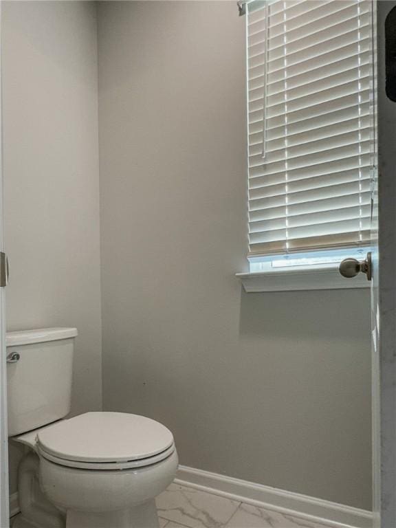 bathroom featuring toilet, marble finish floor, and baseboards