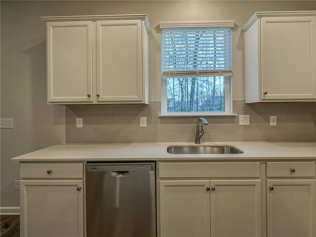 kitchen featuring light countertops, decorative backsplash, stainless steel dishwasher, white cabinets, and a sink