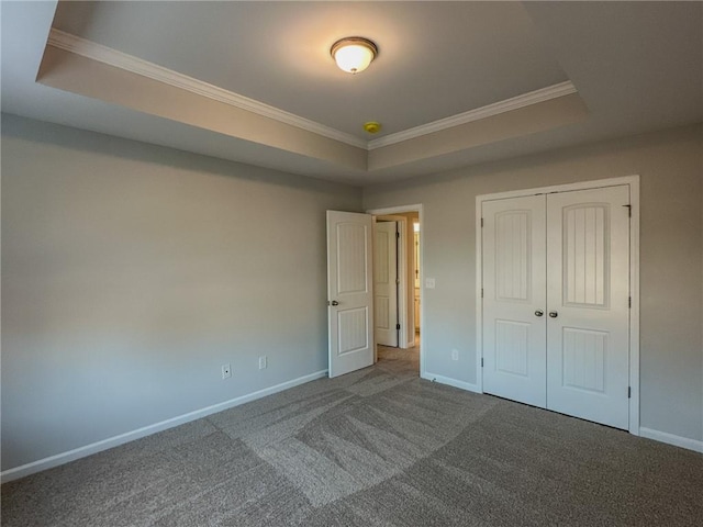 unfurnished bedroom with carpet, a raised ceiling, and baseboards