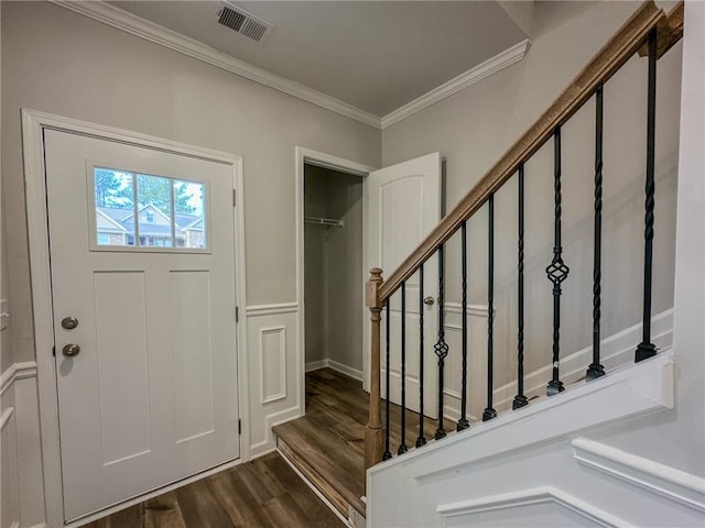 foyer with dark wood-type flooring, visible vents, ornamental molding, and stairway