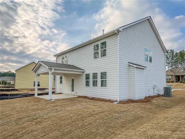 rear view of house featuring central air condition unit, a patio area, and a lawn