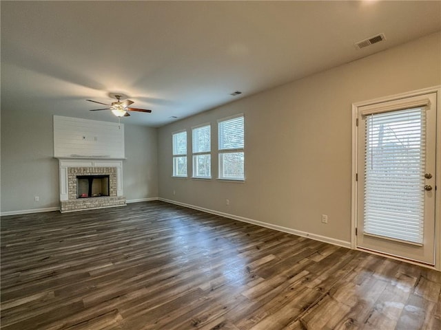 unfurnished living room featuring dark wood-style flooring, a fireplace, visible vents, and baseboards