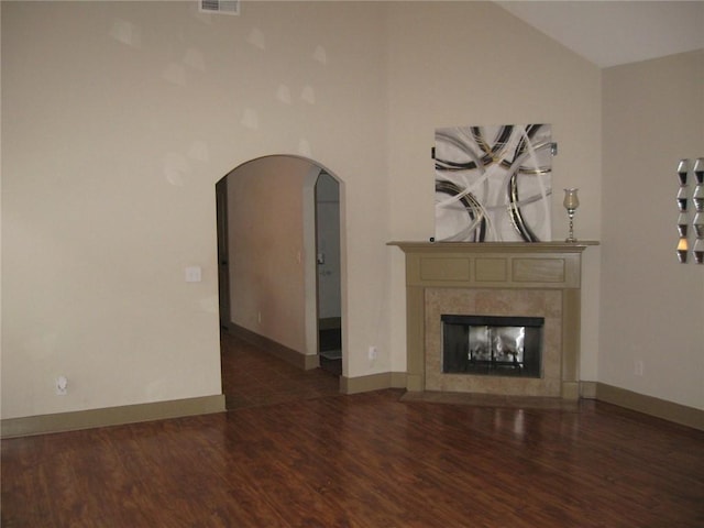 unfurnished living room featuring lofted ceiling, a fireplace, and dark wood-type flooring