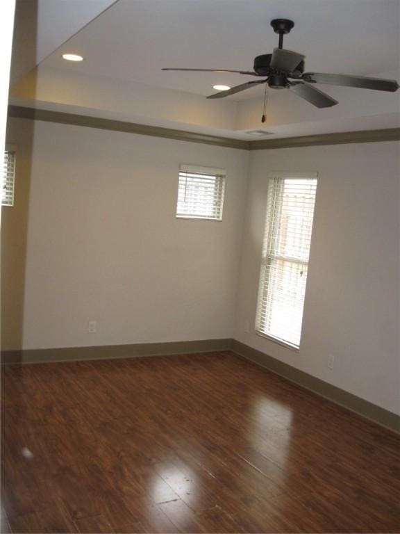 spare room featuring dark hardwood / wood-style floors, crown molding, ceiling fan, and a tray ceiling