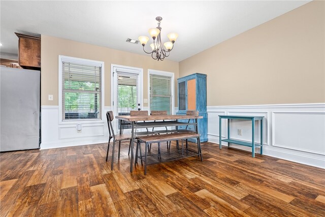 dining space featuring a chandelier, wood finished floors, a wainscoted wall, and a decorative wall