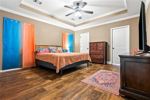 bedroom with a tray ceiling, wood finished floors, crown molding, and ceiling fan