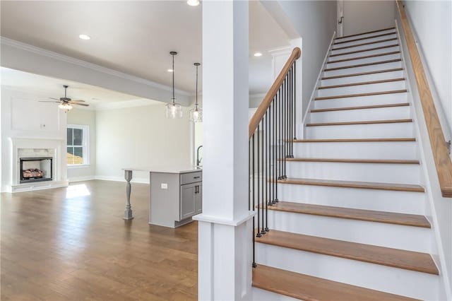 stairway featuring ceiling fan, hardwood / wood-style floors, sink, and ornamental molding