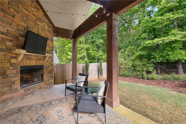 view of patio / terrace featuring an outdoor stone fireplace and a fenced backyard