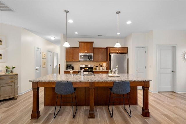 kitchen featuring stainless steel appliances, light wood-type flooring, decorative backsplash, and visible vents