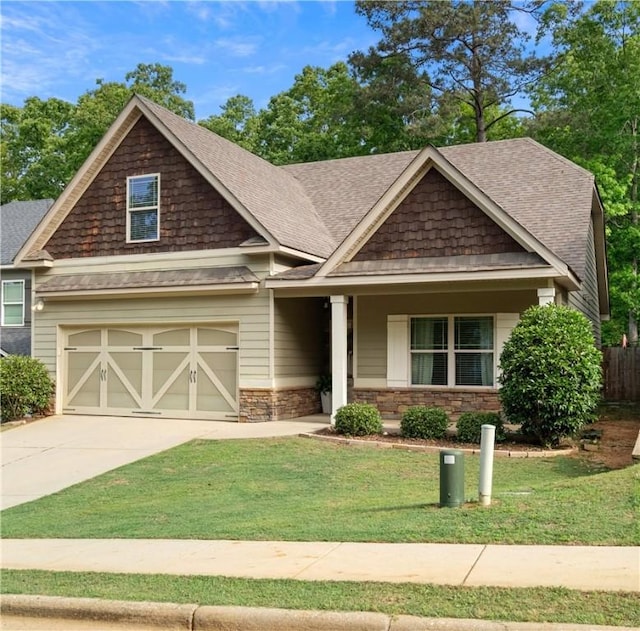 craftsman-style home featuring fence, an attached garage, concrete driveway, a front lawn, and a shingled roof