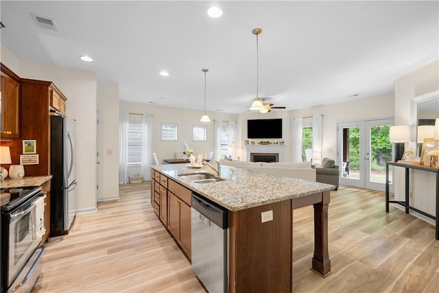 kitchen with light wood finished floors, french doors, a sink, a fireplace, and appliances with stainless steel finishes