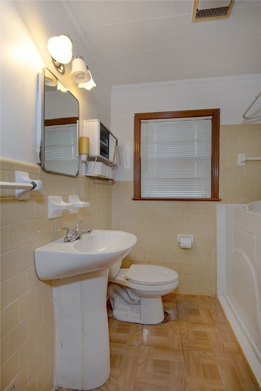 bathroom featuring crown molding, tile walls, and toilet