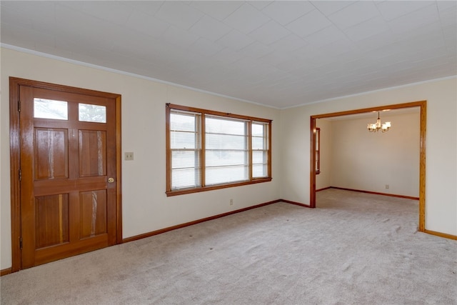 carpeted entrance foyer with ornamental molding and a chandelier