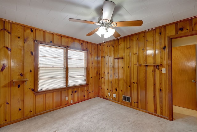 carpeted empty room with wooden walls and ceiling fan