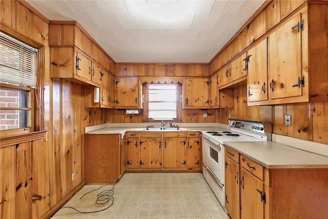 kitchen with sink, white electric range, and wood walls