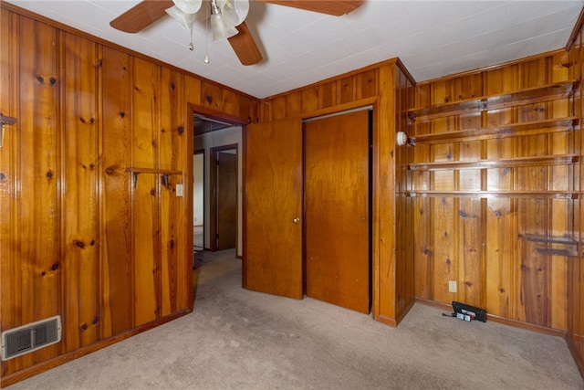 unfurnished bedroom with a closet, light carpet, and wood walls