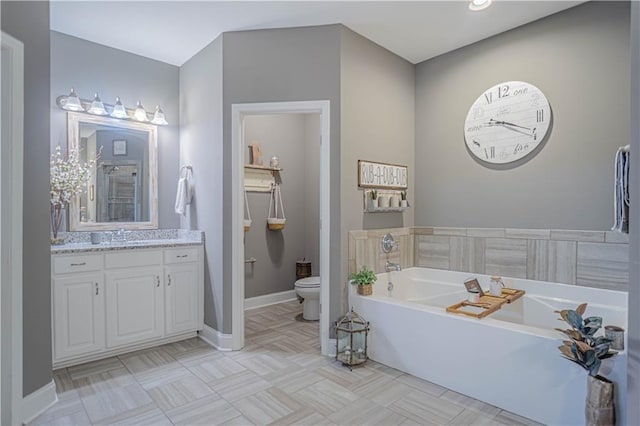 bathroom featuring tile patterned flooring, vanity, toilet, and a tub to relax in