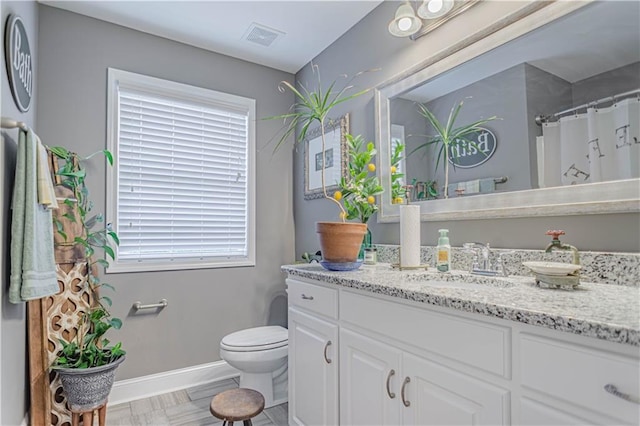 bathroom featuring a shower with shower curtain, vanity, toilet, and a wealth of natural light