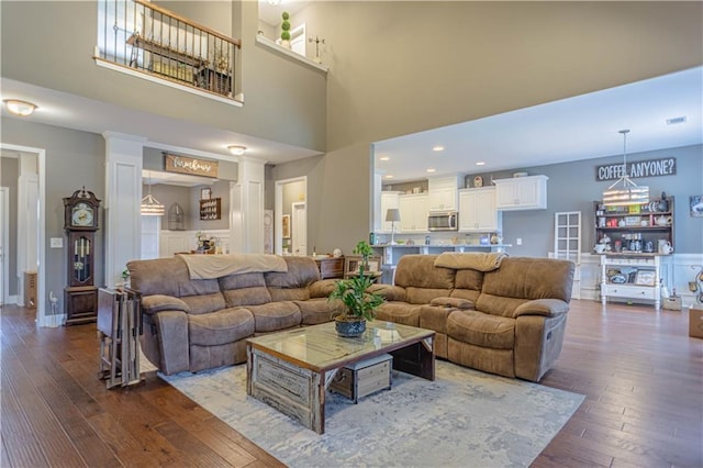 living room featuring a towering ceiling and dark wood-type flooring