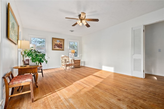 living area with wood-type flooring and ceiling fan