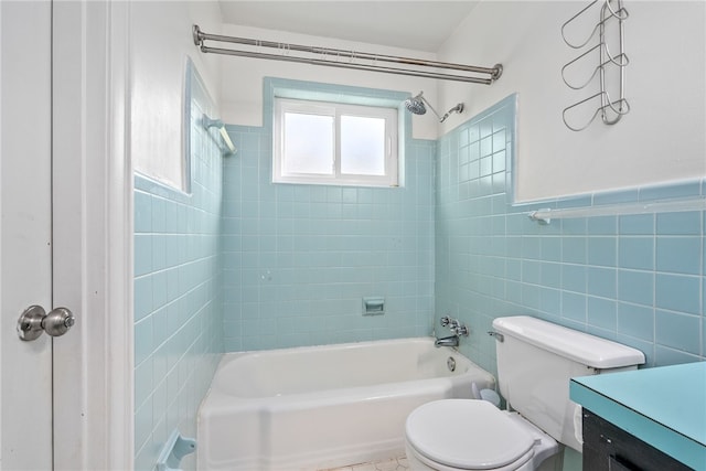 full bathroom with vanity, toilet, tiled shower / bath combo, and tile walls