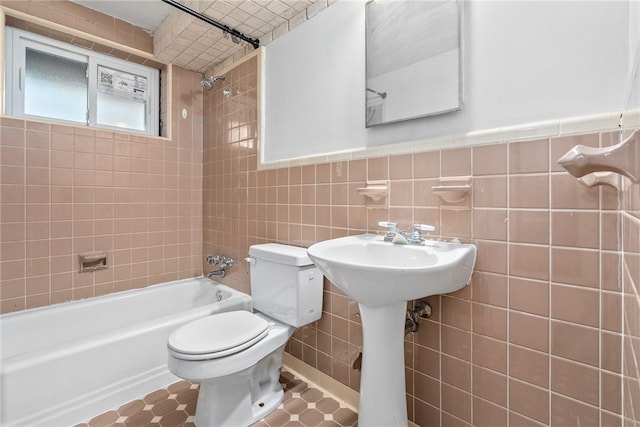 bathroom with tile walls, tiled shower / bath, and toilet