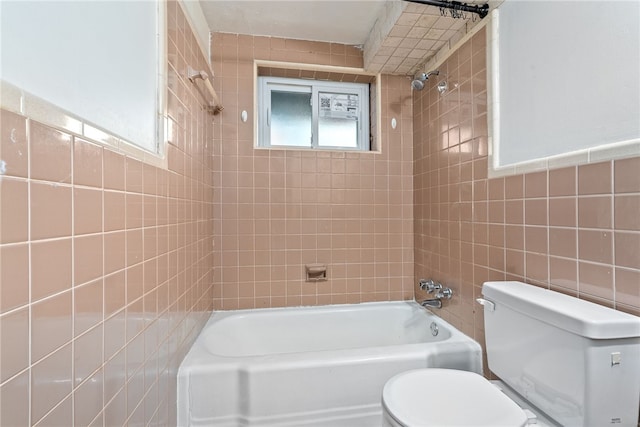 bathroom with tiled shower / bath combo, tile walls, and toilet