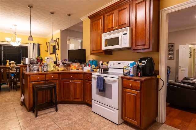 kitchen featuring a notable chandelier, kitchen peninsula, pendant lighting, white appliances, and ornamental molding