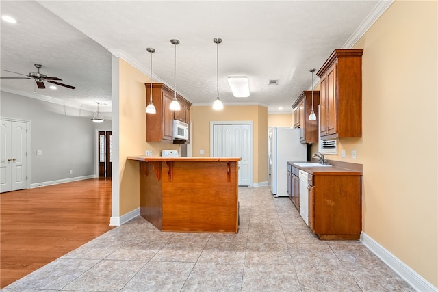 kitchen with a ceiling fan, ornamental molding, a sink, white appliances, and brown cabinetry