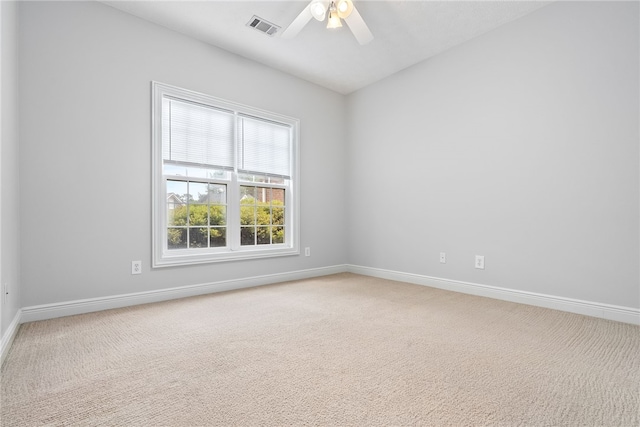 carpeted spare room featuring baseboards, visible vents, and ceiling fan