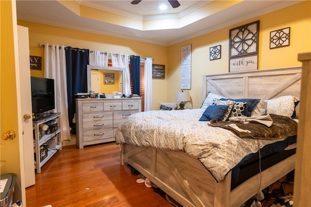 bedroom featuring a tray ceiling, crown molding, ceiling fan, and hardwood / wood-style flooring