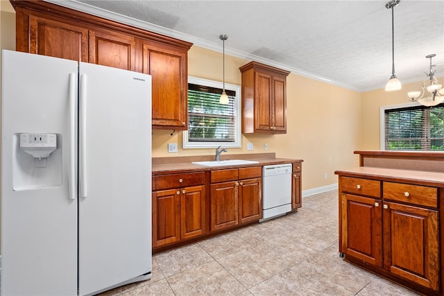 kitchen with brown cabinets, a sink, white appliances, decorative light fixtures, and crown molding