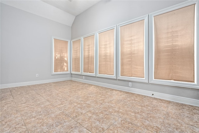 spare room featuring vaulted ceiling, baseboards, and tile patterned flooring