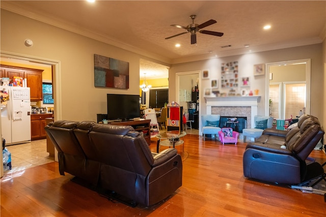 living room with ceiling fan with notable chandelier, light hardwood / wood-style flooring, and crown molding