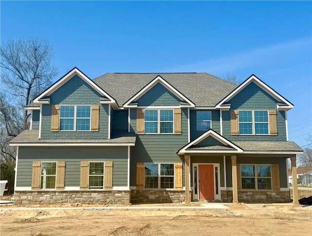 craftsman-style home with stone siding and roof with shingles