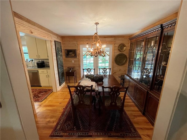 dining area featuring light hardwood / wood-style floors, an inviting chandelier, and wooden walls