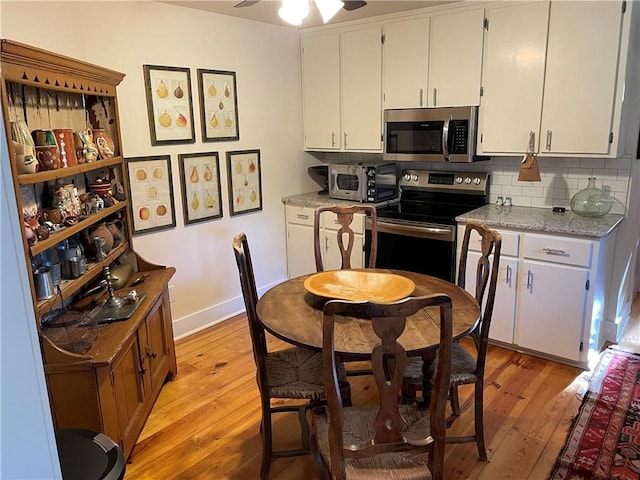 kitchen featuring decorative backsplash, stainless steel appliances, white cabinetry, and light hardwood / wood-style floors