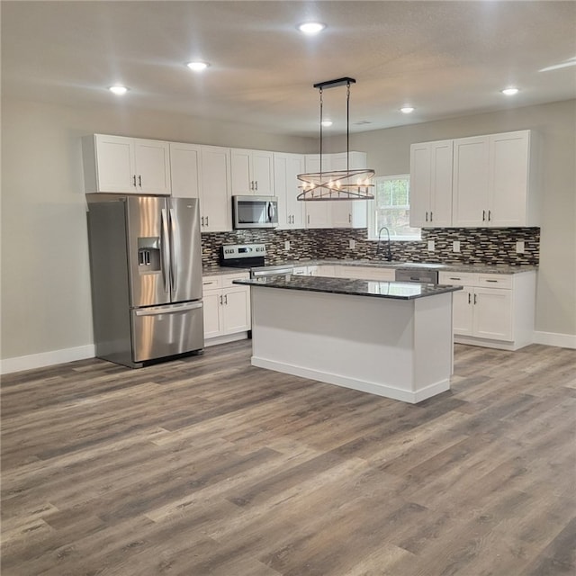 kitchen featuring white cabinetry, decorative light fixtures, and appliances with stainless steel finishes