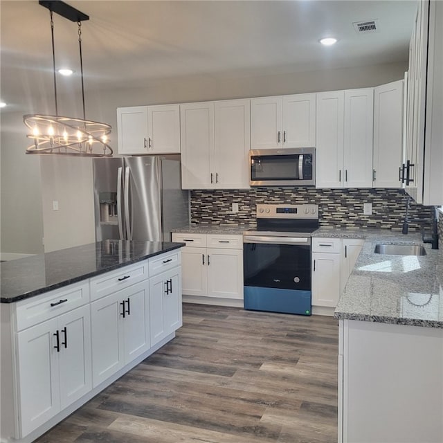 kitchen featuring white cabinetry, appliances with stainless steel finishes, and decorative light fixtures