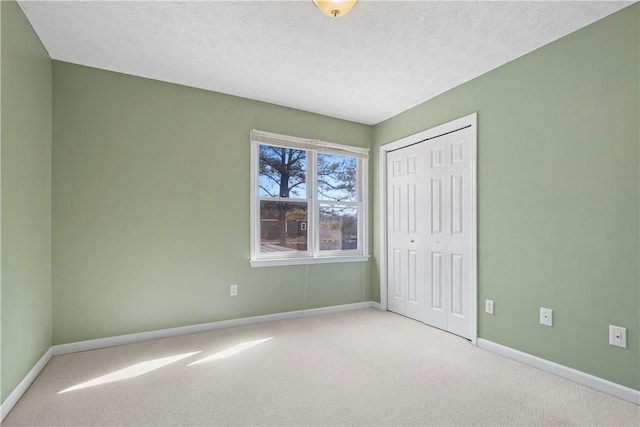 unfurnished bedroom with light colored carpet, a closet, and a textured ceiling