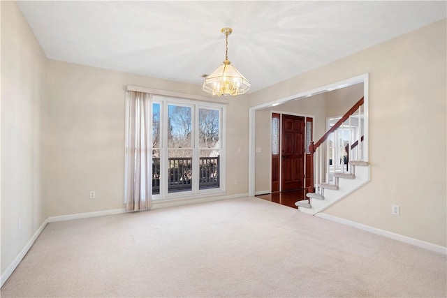 spare room featuring an inviting chandelier and carpet flooring