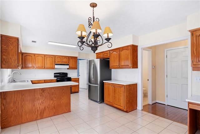 kitchen featuring pendant lighting, black electric range oven, light tile patterned floors, stainless steel fridge, and sink