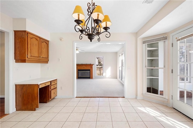 kitchen with ceiling fan with notable chandelier, light carpet, and pendant lighting