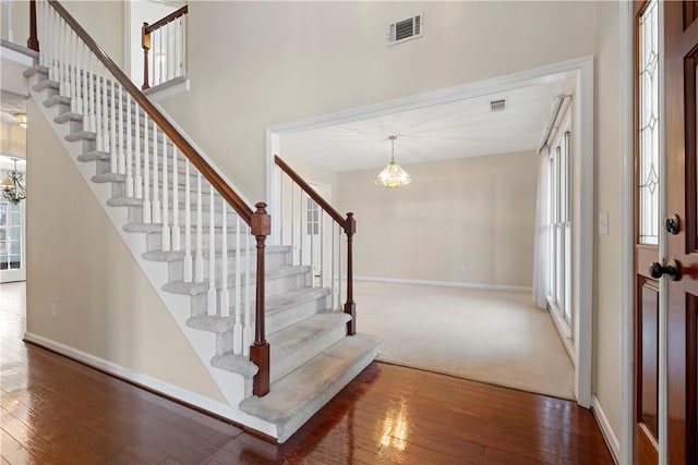 foyer entrance featuring plenty of natural light, dark hardwood / wood-style floors, and a chandelier