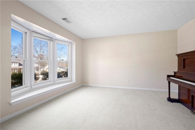 living room with plenty of natural light, light colored carpet, and a textured ceiling